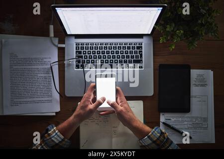 Person, programming and laptop with phone in office with typing for mockup space, coding and software script. Top view, technology expert and employee Stock Photo