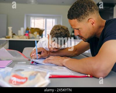 Father assisting son doing homework at home Stock Photo