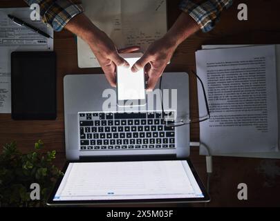 Businessman, programmer and typing on phone screen in office with laptop for data analytics, coding and software script. Top view, tech expert and Stock Photo