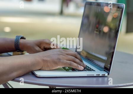 Close up of mans hands using laptop on outdoor table Stock Photo