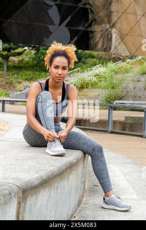 Sporty young woman tying shoelace Stock Photo