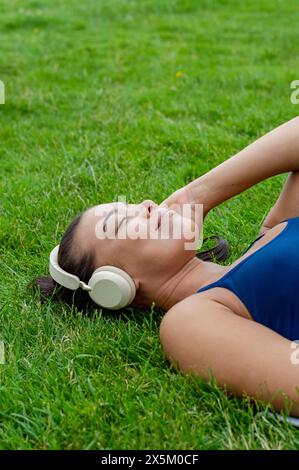 Woman in headphones lying on grass Stock Photo