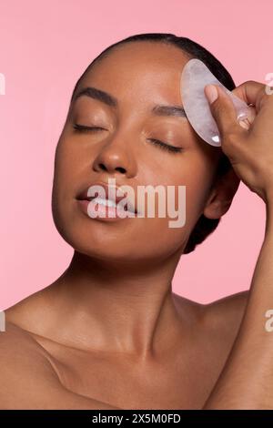 Young woman using face massager Stock Photo
