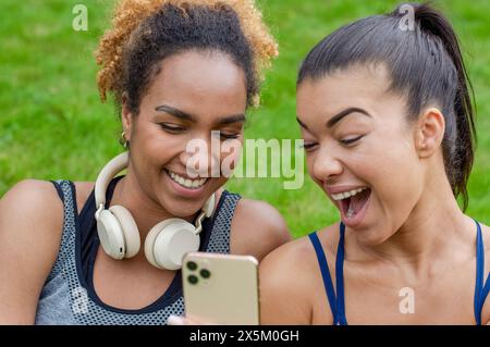 Two women laughing while sharing smart phone Stock Photo