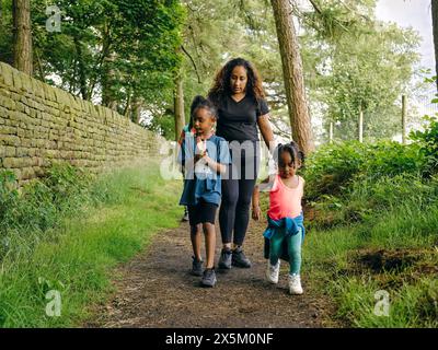Mother with daughters walking on footpath through forest Stock Photo