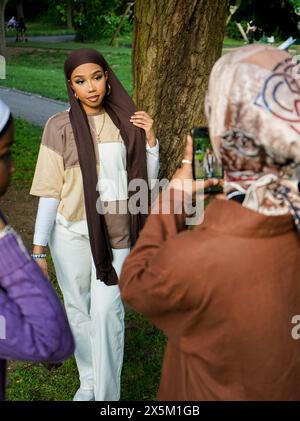 UK, London, Young woman wearing hijab photographing friend in park Stock Photo