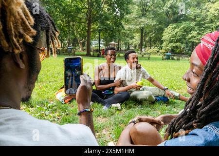 USA, Couple sitting on lawn in park with friends Stock Photo