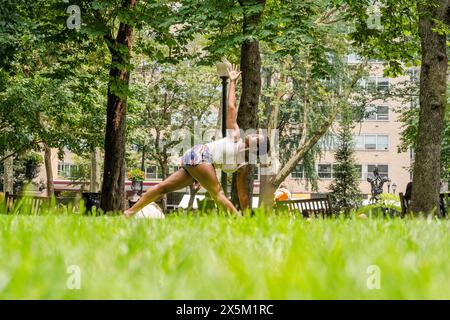 USA, Young woman practicing yoga on lawn in park Stock Photo