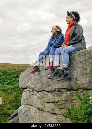 Female hikers sitting on rocks and looking at landscape Stock Photo