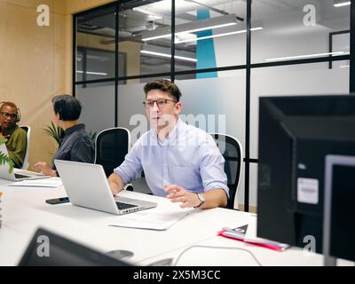 Office workers using computers in co-working office space Stock Photo