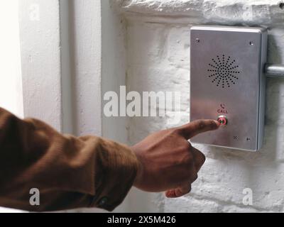 Close-up of mans hand pushing intercom button Stock Photo