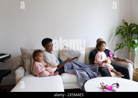Family with daughters watching TV on sofa Stock Photo