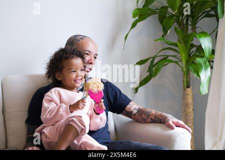 Father and daughter sitting on sofa Stock Photo