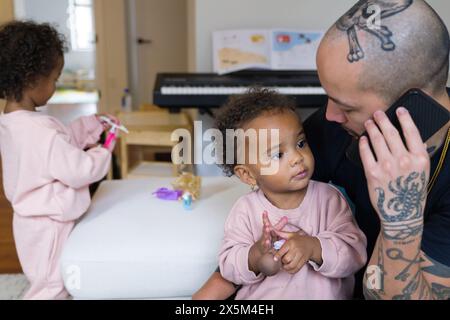 Father talking on phone and taking care of daughters Stock Photo