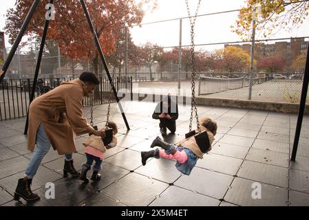 Parents with daughters on swing Stock Photo