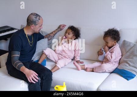 Father and daughters sitting on sofa Stock Photo