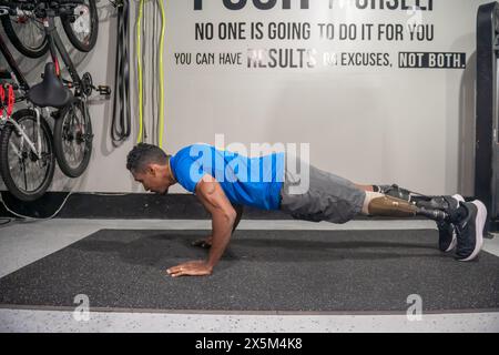 Man with prosthetic leg doing push-ups in gym Stock Photo