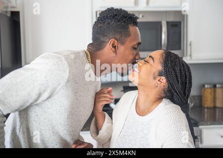 Smiling couple kissing in kitchen Stock Photo