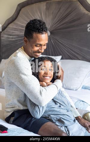 Father with prosthetic leg embracing son in bedroom Stock Photo