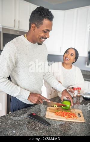 Smiling couple preparing food in kitchen Stock Photo