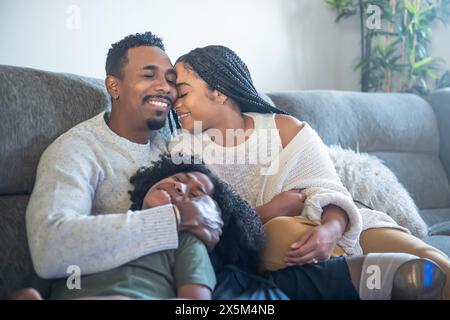 Mother and father with prosthetic leg hugging son on sofa Stock Photo