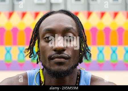 Portrait of smiling man with braided hair against colorful background Stock Photo