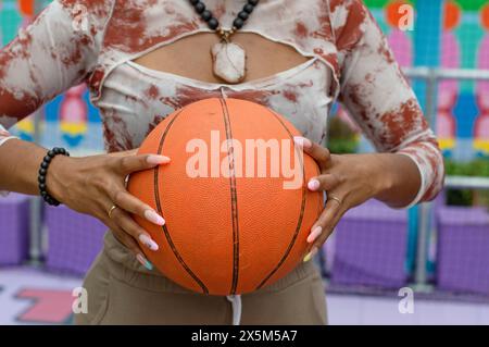 Mid section of woman in holding basketball ball Stock Photo