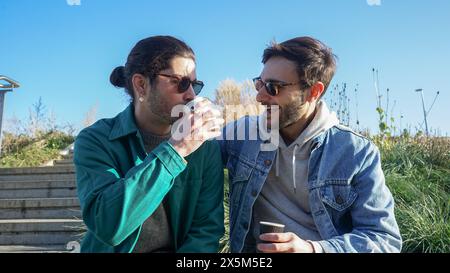 Smiling gay couple relaxing on bench Stock Photo