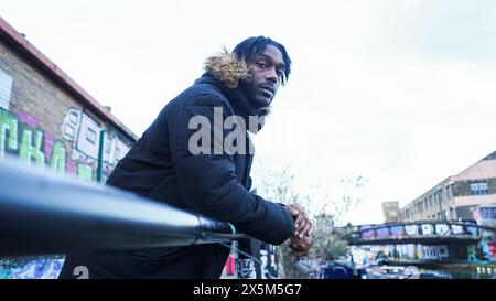 Portrait of young man leaning on railing in city Stock Photo
