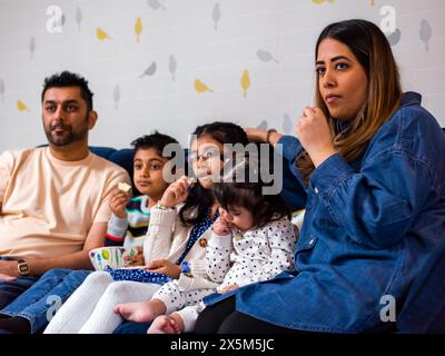 Parents with children sitting on sofa and watching TV Stock Photo