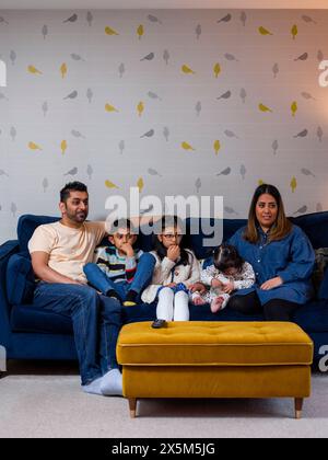 Parents with children sitting on sofa and watching TV Stock Photo