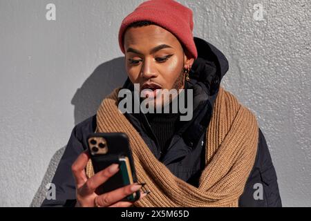 USA, New York City, Queer man in warm clothing looking at smart phone Stock Photo