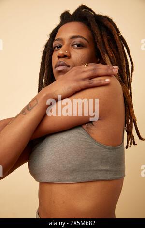 Studio shot of woman with dreadlocks stretching arm Stock Photo