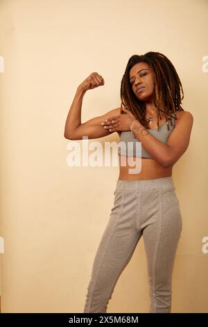 Studio shot of woman with dreadlocks flexing muscles Stock Photo