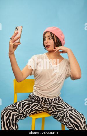 Studio shot of stylish woman with smart phone against blue background Stock Photo