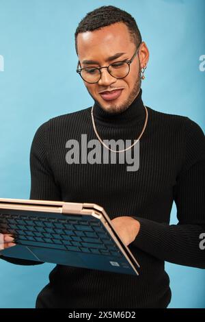 Studio portrait of smiling queer man using laptop Stock Photo