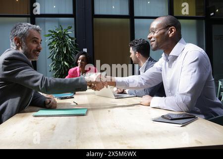 Businessmen shaking hands at business meeting Stock Photo