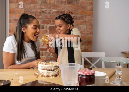 Mother and son eating cake in kitchen Stock Photo