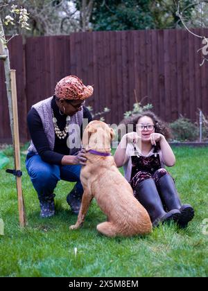 Mother and daughter with dog in backyard Stock Photo