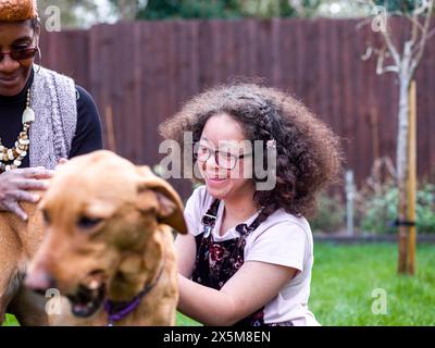 Mother and daughter with dog in backyard Stock Photo