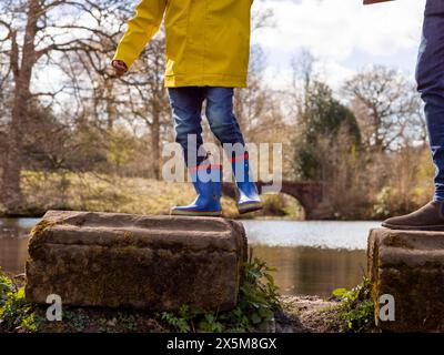 Father with son on stepping stones on lake, low section Stock Photo