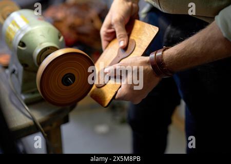 young man working on Electric Leather Burnisher Machine, close up side view cropped shot Stock Photo
