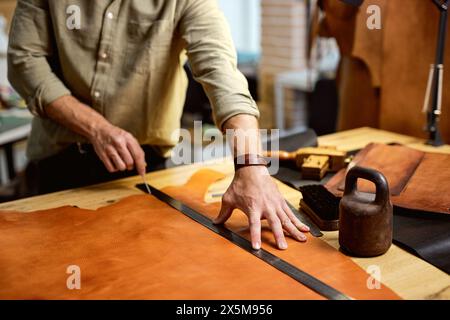 skilled master crafting a new handmade leather wallet in the leather workshop.close up cropped shot. hobby, interests Stock Photo