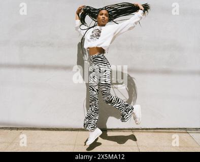 Young woman with long dreadlocks jumping Stock Photo