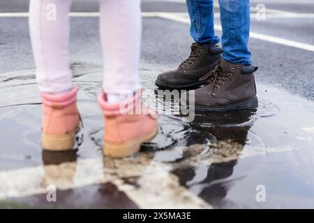 Girl and boy standing in puddle Stock Photo