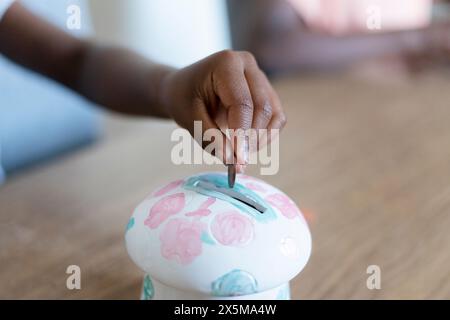 Girl putting coin in piggy bank Stock Photo