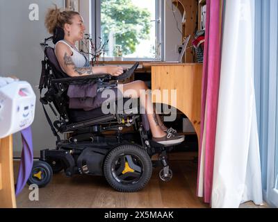 Woman in electric wheelchair working on laptop Stock Photo