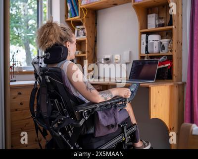 Woman in electric wheelchair working on laptop Stock Photo