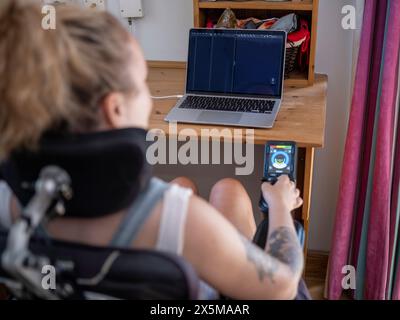 Woman in electric wheelchair working on laptop Stock Photo