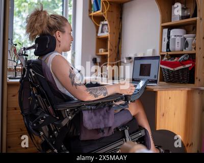 Woman in electric wheelchair working on laptop Stock Photo